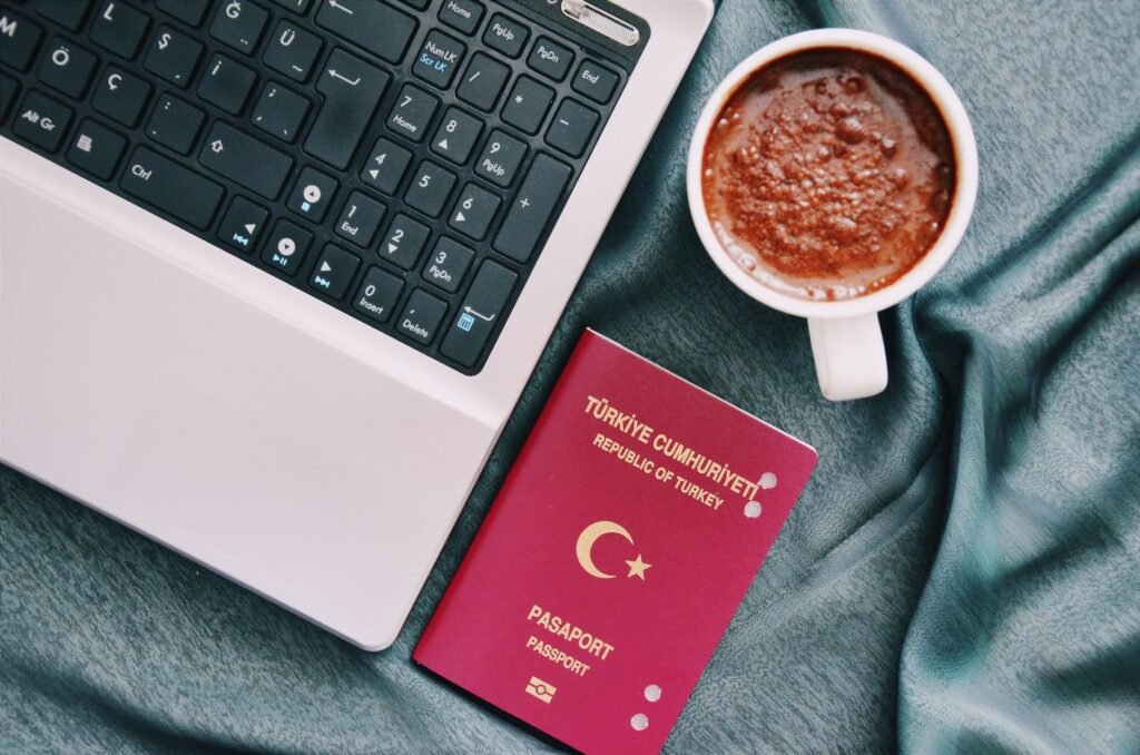 Turkish passport beside a laptop and coffee, representing travel preparation and insurance planning for visitors to Turkey.